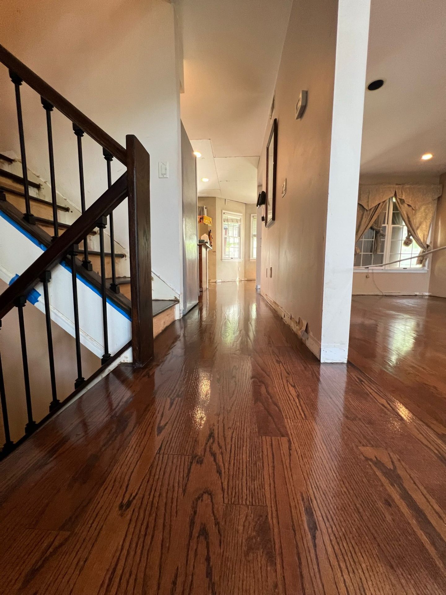 Refinished hardwood floor with staircase and iron balusters