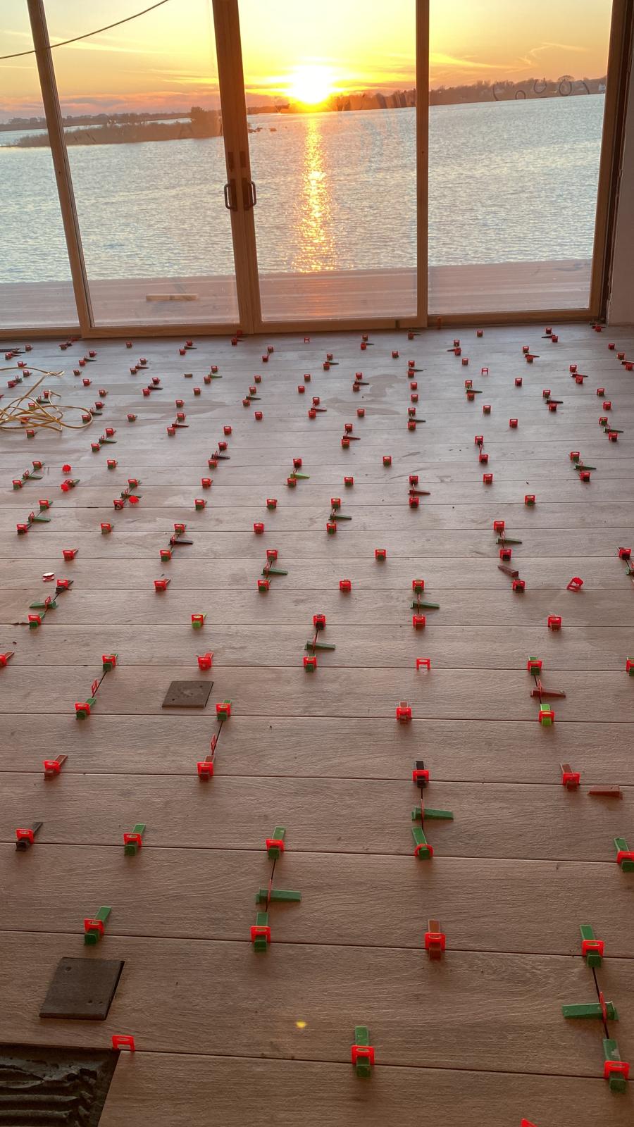 Large-format wood-look tile installation with leveling clips at sunset