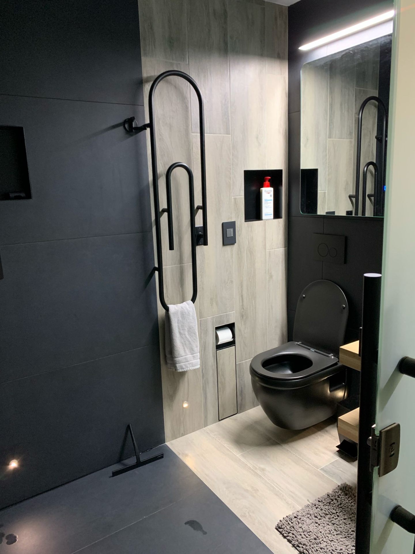 Modern bathroom with black fixtures and wood-look tile accent wall
