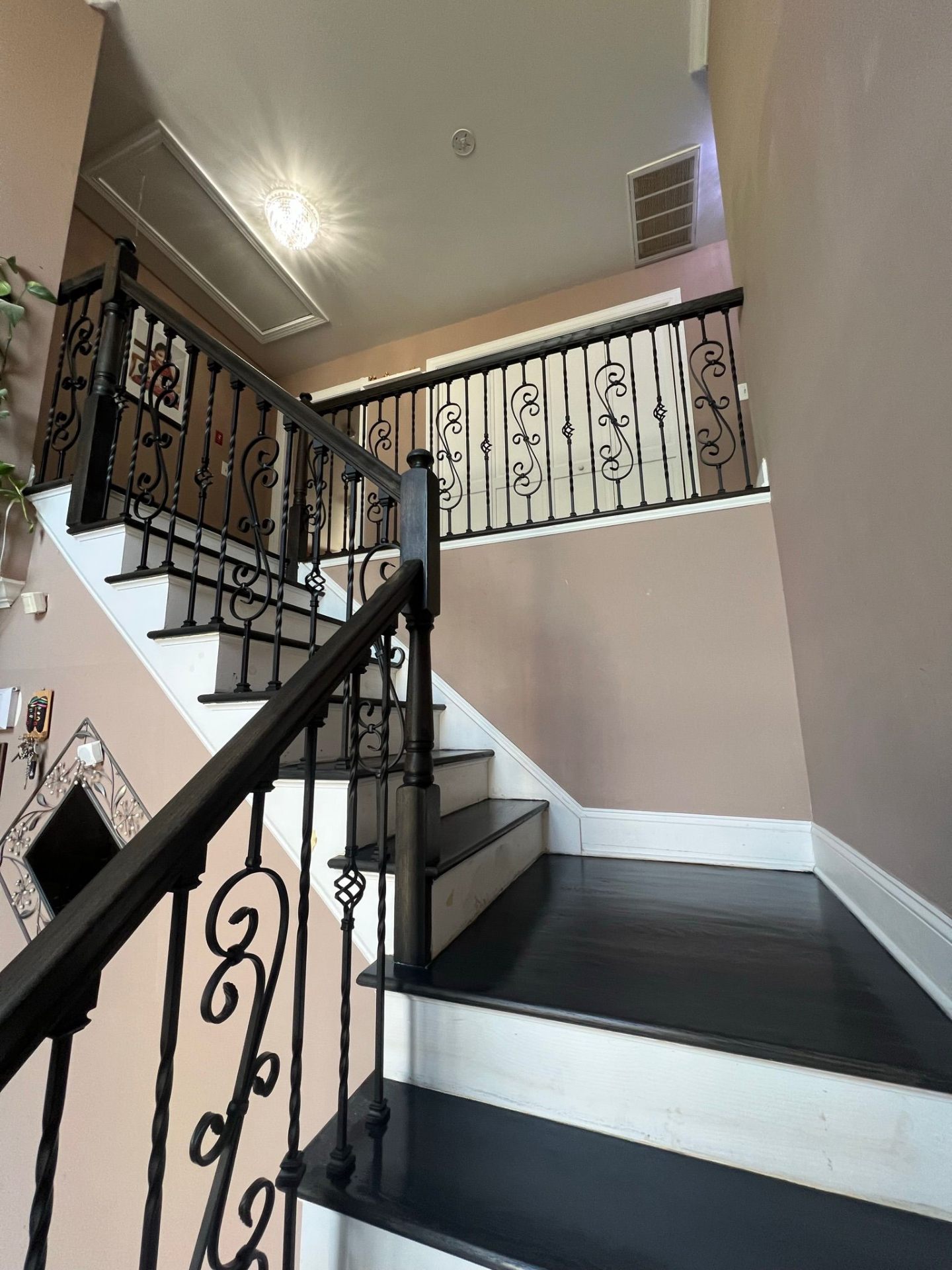 Refinished staircase with black treads, white risers, and wrought iron balusters