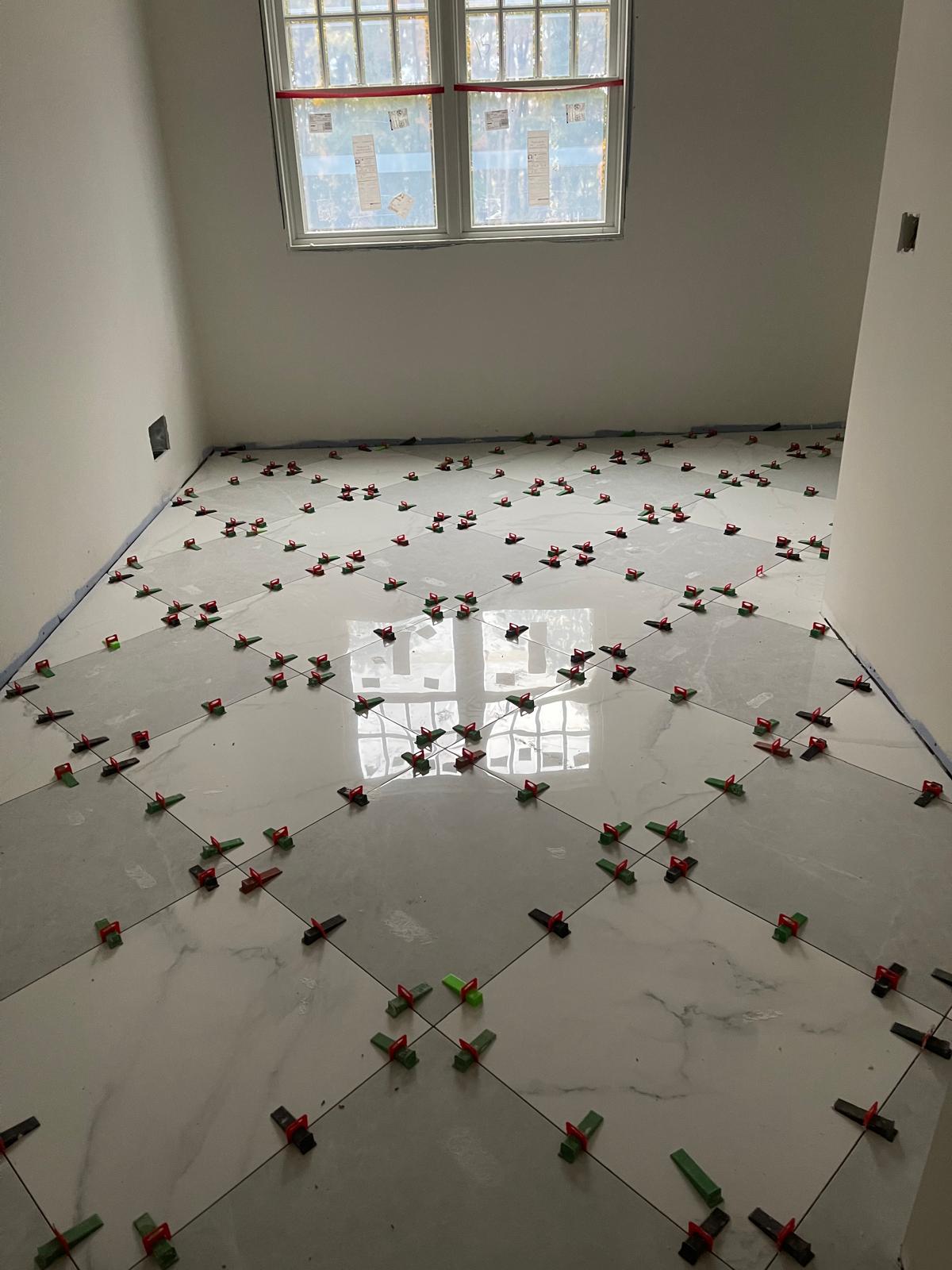 Large-format marble-look porcelain tile floor with leveling clips