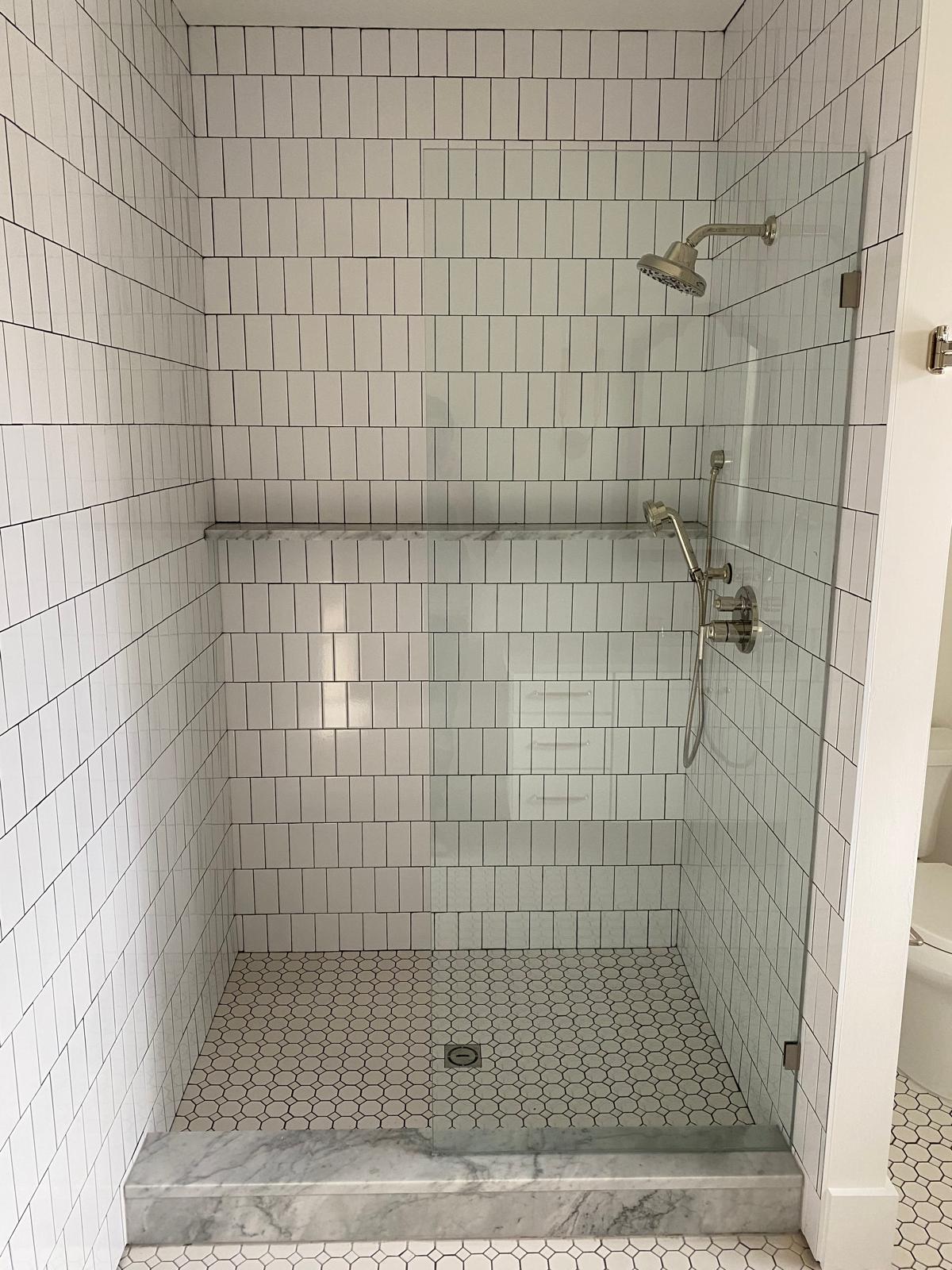 Vertical stack white subway tile shower with hexagon mosaic floor