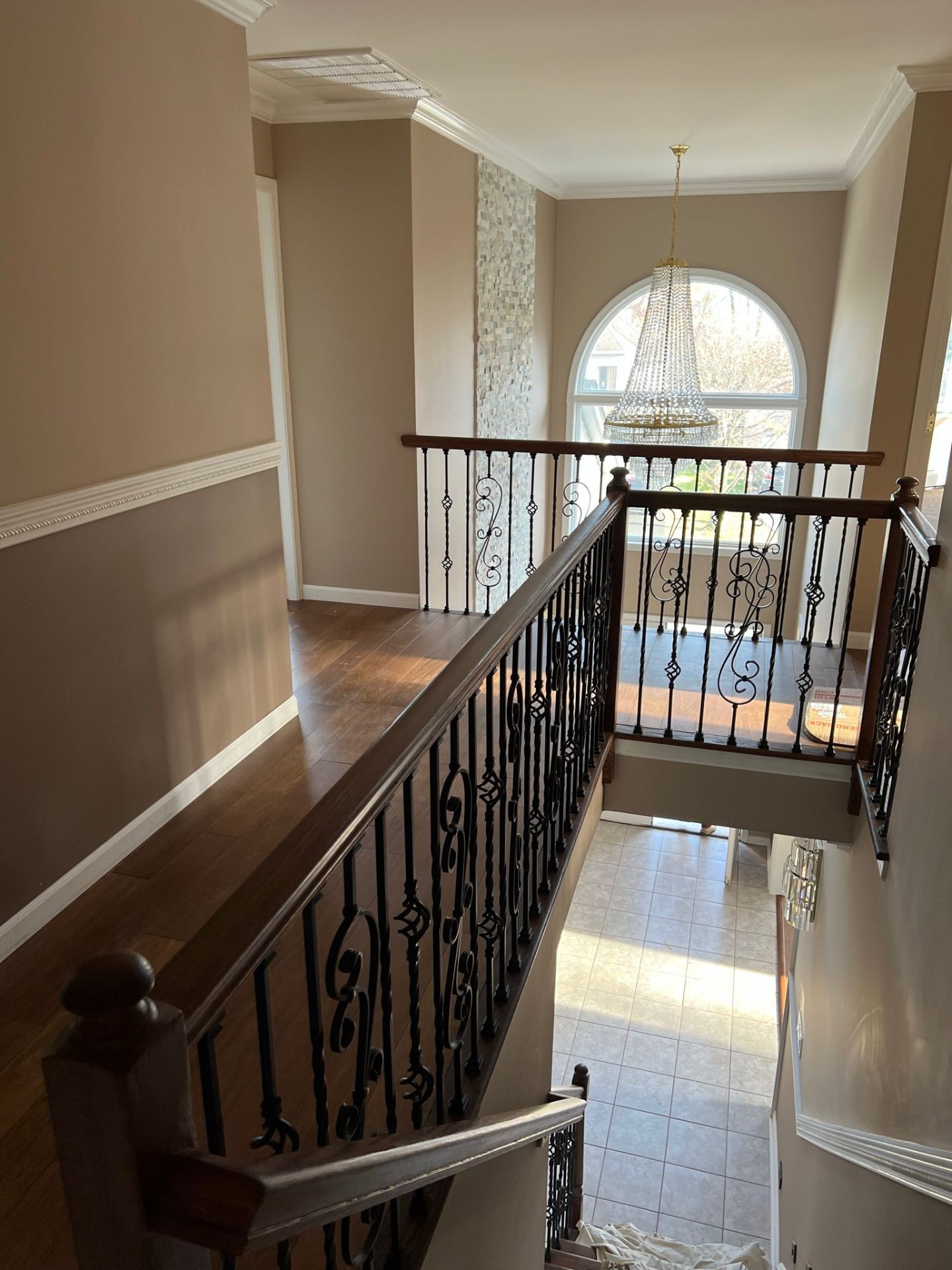 Upstairs hallway with dark hardwood floor and wrought iron railing