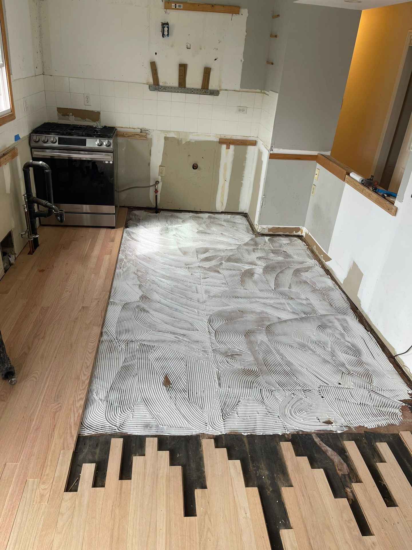 Hardwood installation in progress with adhesive laid
