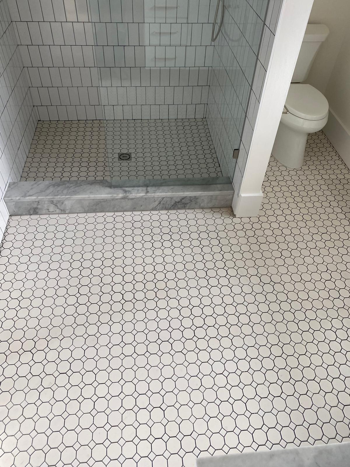 Classic white hexagon tile bathroom floor with marble threshold